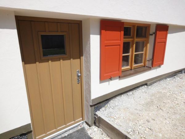 Sprossenfenster Holz mit orangenen Klappläden und Holz-Haustür